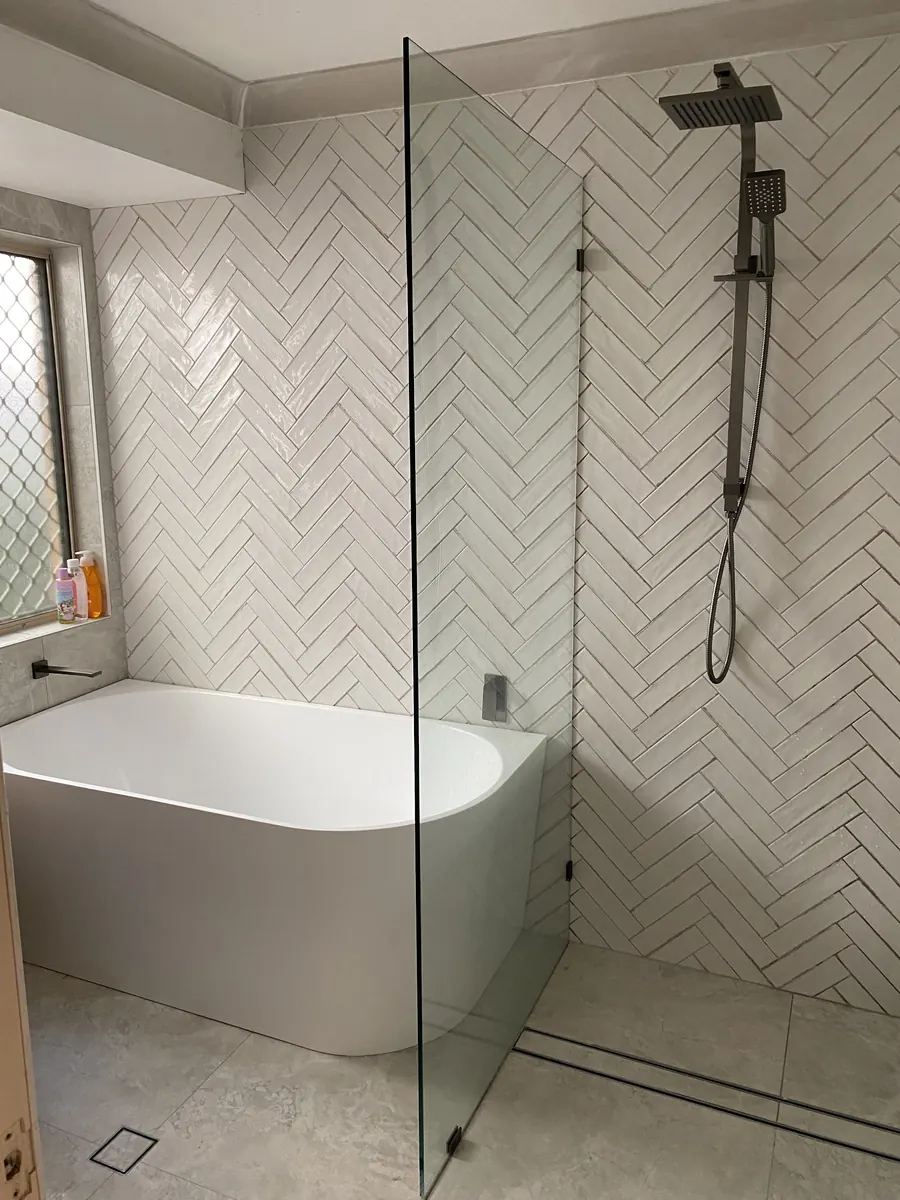 White herringbone wall tiles behind a freestanding bath and walk-in shower