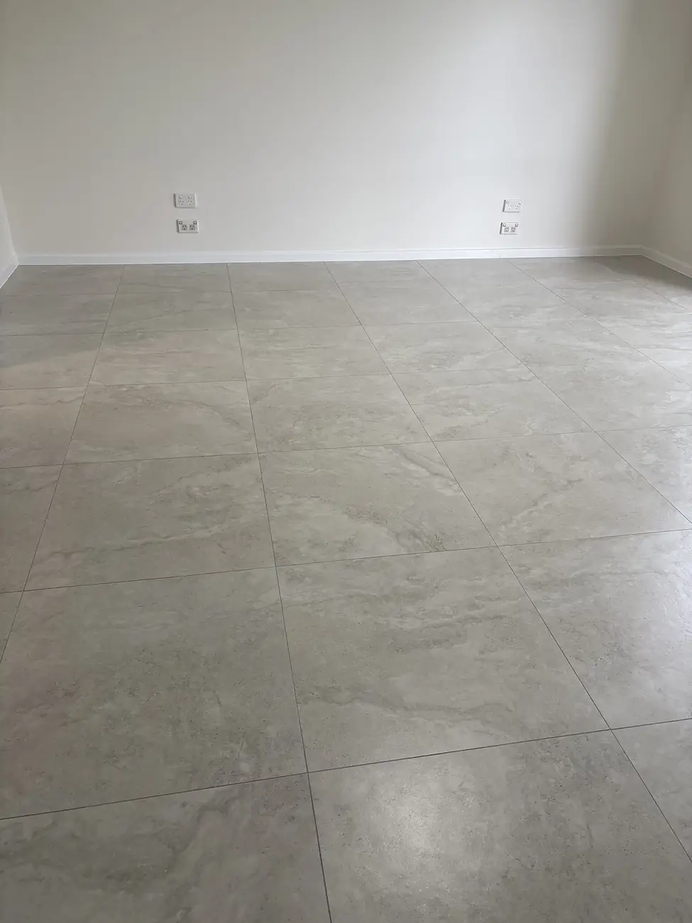 Large-format grey floor tiles laid across an empty room