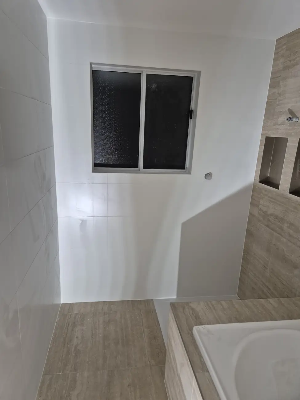 White gloss walls and the tiled bath surround below the window