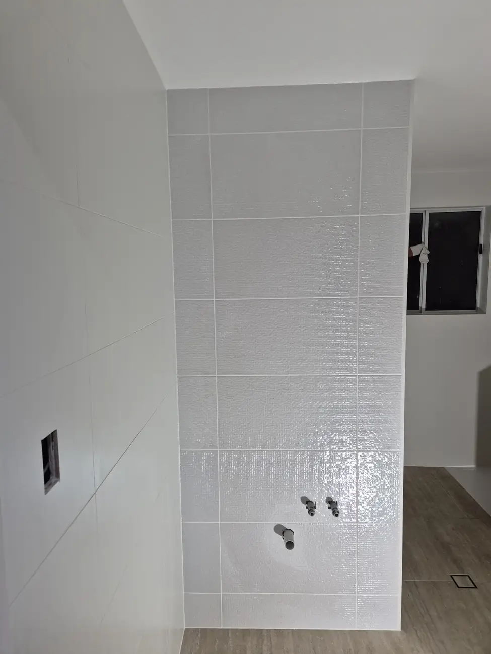 White gloss feature wall with a tiled floor waste