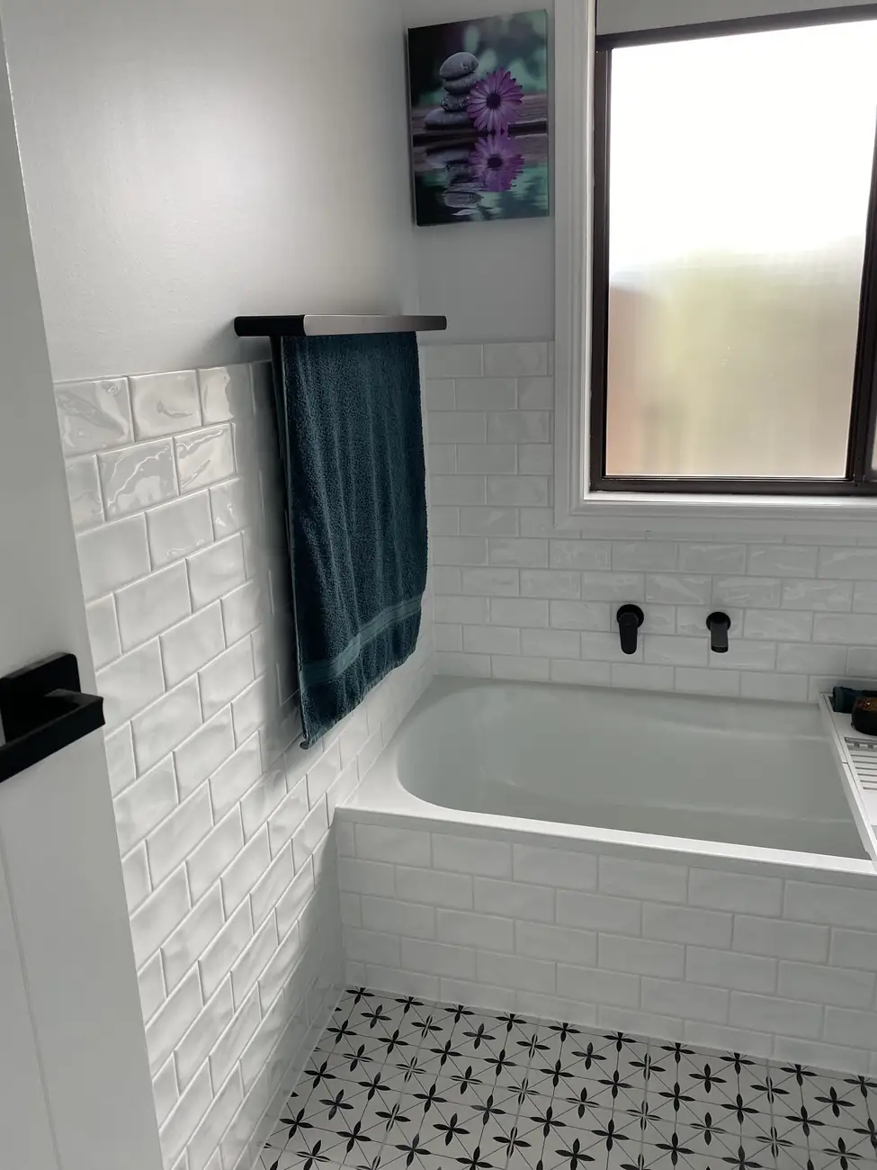 Close-up of the white subway tiles and patterned floor around the bath