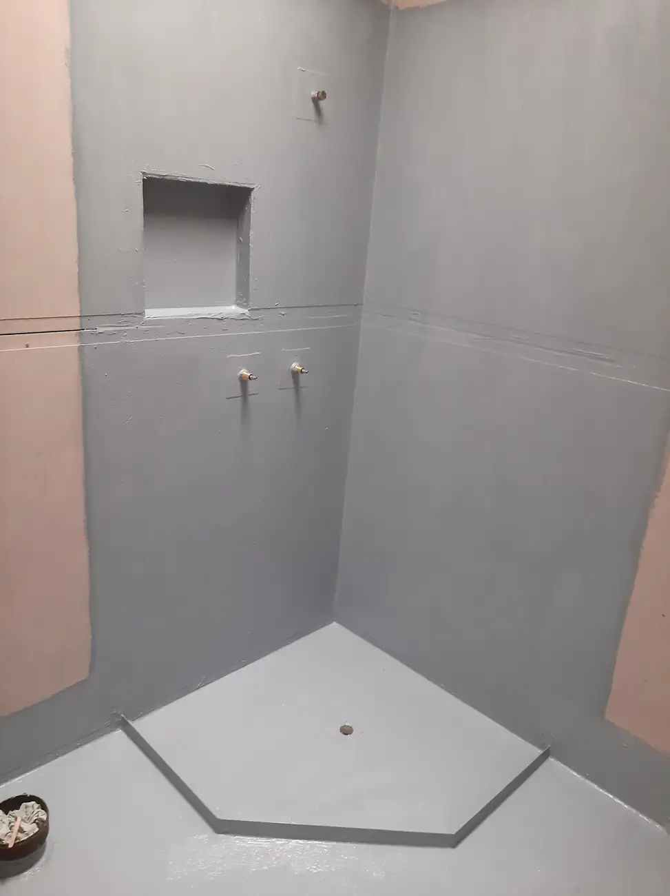 Shower recess waterproofed before tiling: grey membrane on the walls, a lined niche, a waterstop angle and the floor waste